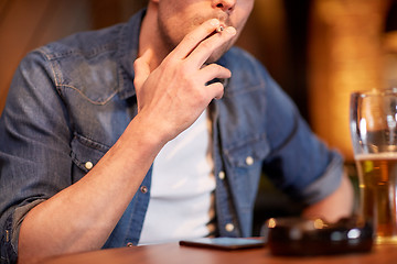 Image showing man drinking beer and smoking cigarette at bar