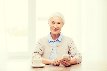 Image showing senior woman with smartphone texting at home