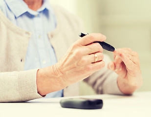 Image showing senior woman with glucometer checking blood sugar