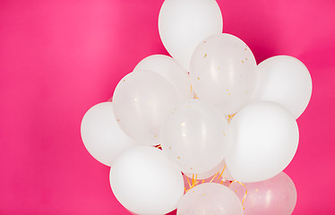 Image showing close up of white helium balloons over pink