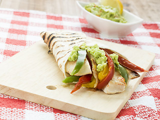 Image showing delicious wrap tortilla with spicy chicken vegetables guacamole