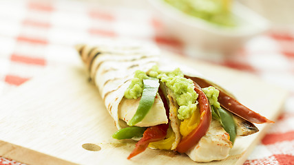 Image showing delicious wrap tortilla with spicy chicken vegetables guacamole