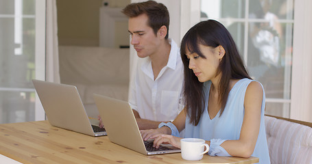 Image showing Calm young couple sitting at table using laptop