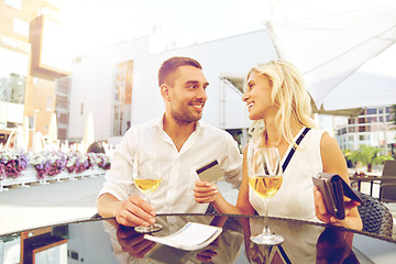 Image showing happy couple with wallet paying bill at restaurant