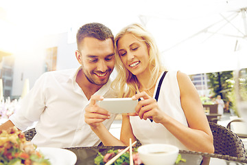 Image showing happy couple with smatphone at restaurant terrace