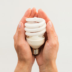 Image showing close up of hands holding energy saving lightbulb