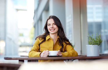 Image showing happy woman drinking cocoa at city street cafe