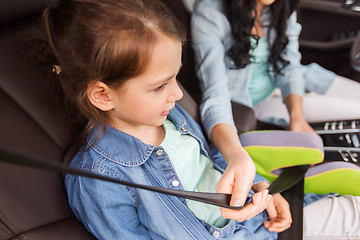 Image showing happy woman fastening child with seat belt in car