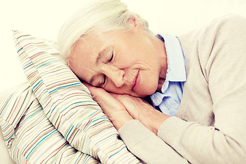 Image showing happy senior woman sleeping on pillow at home