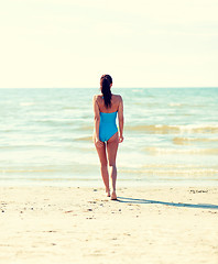 Image showing young woman in swimsuit walking on beach
