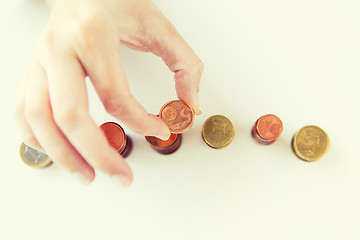 Image showing close up of female hand putting coins into columns