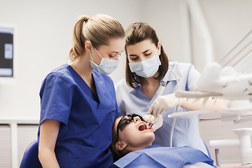 Image showing female dentists treating patient girl teeth