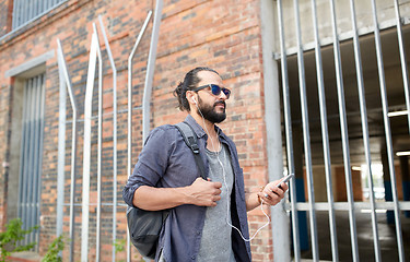 Image showing man with earphones and smartphone walking in city