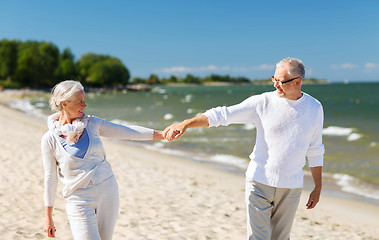 Image showing happy senior couple holding hands on summer beach