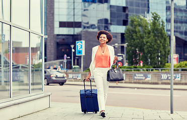 Image showing happy young african woman with travel bag in city