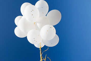 Image showing close up of white helium balloons in blue sky