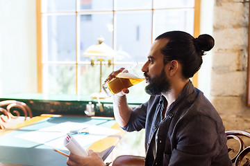 Image showing man with notebook drinking beer at bar or pub