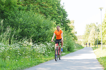 Image showing happy young man riding bicycle outdoors