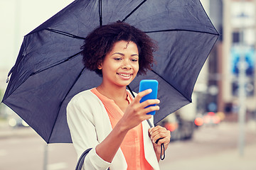 Image showing businesswoman with umbrella texting on smartphone