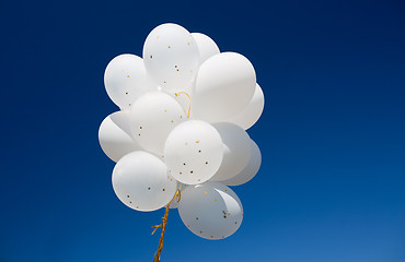 Image showing close up of white helium balloons in blue sky