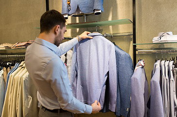 Image showing close up of man choosing jacket at clothing store