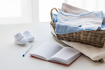 Image showing close up of baby clothes for newborn and notebook