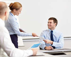 Image showing smiling woman giving papers to man in office