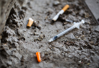 Image showing close up of syringe and smoked cigarette on ground