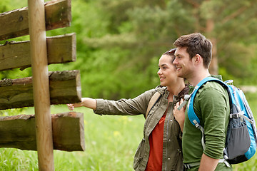 Image showing smiling couple at signpost with backpacks hiking