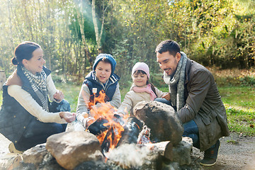 Image showing happy family roasting marshmallow over campfire