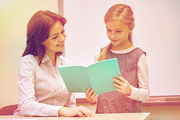 Image showing school girl with notebook and teacher in classroom