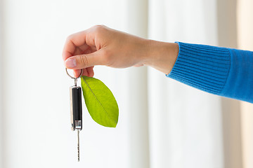 Image showing close up of hand holding car key with green leaf