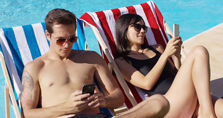 Image showing Young couple using phones at the swimming pool