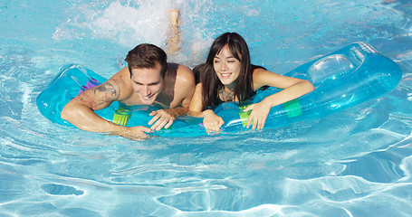 Image showing Joyful couple swimming together on floatie in pool