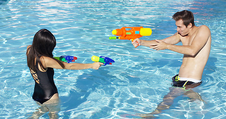 Image showing Happy couple shooting off water guns in pool