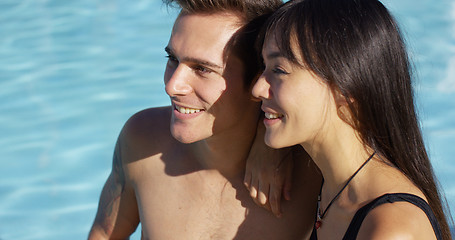 Image showing Sunbathing couple sit beside swimming pool