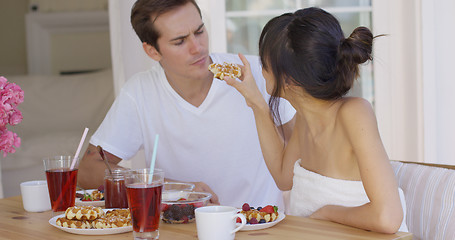 Image showing Woman trying to feed annoyed man a waffle