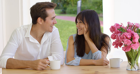 Image showing Laughing young adult couple sitting at table