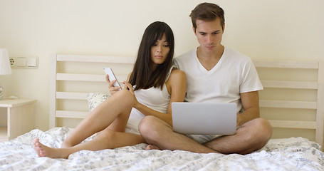 Image showing Young serious couple sitting together in bed