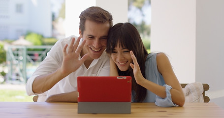 Image showing Man and woman waving at their tablet computer