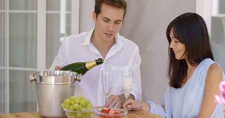 Image showing Smiling young couple pouring champagne to drink
