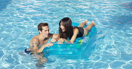 Image showing Happy young couple floating on mattress in pool