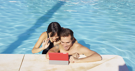 Image showing Smiling couple in swimming pool use digital device