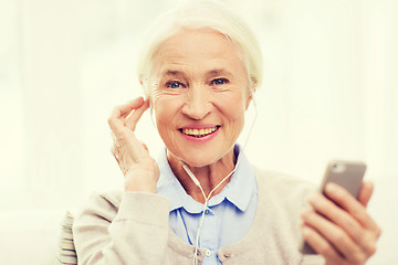 Image showing senior woman with smartphone and earphones at home