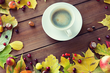 Image showing close up of coffee cup on table with autumn leaves