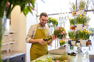 Image showing smiling florist man making bunch at flower shop