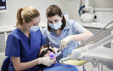 Image showing female dentists treating patient girl teeth