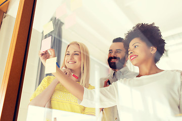 Image showing happy creative team writing on stickers at office