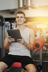 Image showing smiling young man with tablet pc computer in gym