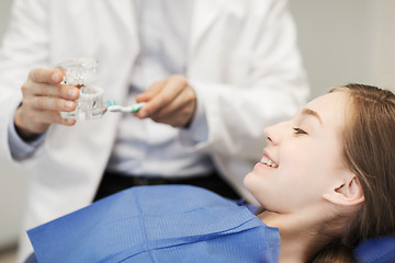 Image showing happy dentist showing jaw layout to patient girl